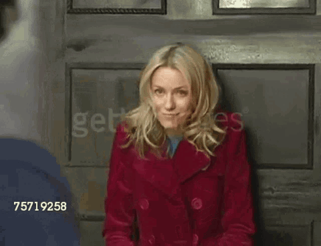a woman in a red coat is being photographed by a man with the number 75719258 on the bottom right