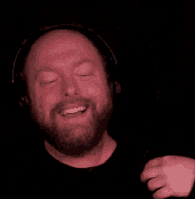 a bald man with a beard wearing headphones and smiling .