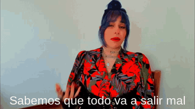 a woman with blue hair is sitting in a chair with the words sabemos que todo va a salir mal