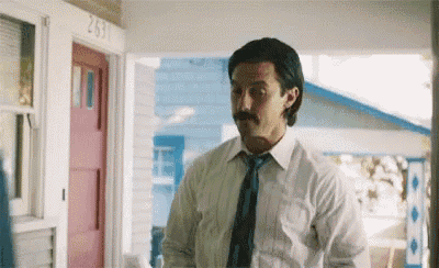 a man with a mustache is standing on a porch .