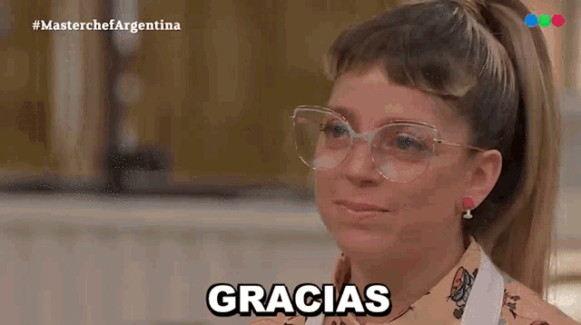 a woman wearing glasses and earrings says gracias in spanish