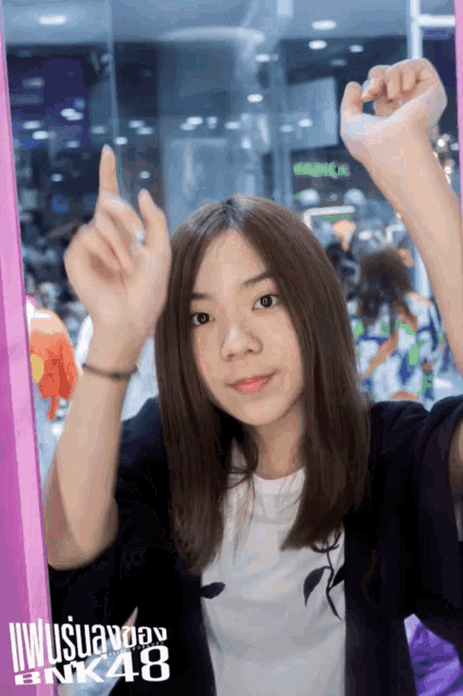 a girl with her arms in the air behind a sign that says ' bnk48 '