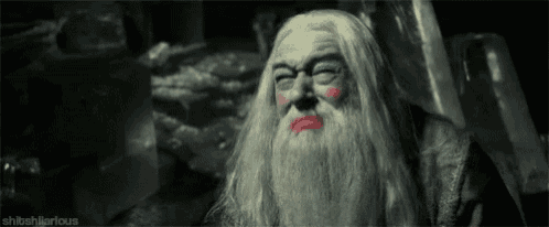 a man with a beard and makeup on his face is sitting in a chair in a dark room .