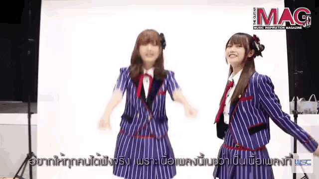 two girls are dancing in front of a sign that says mag