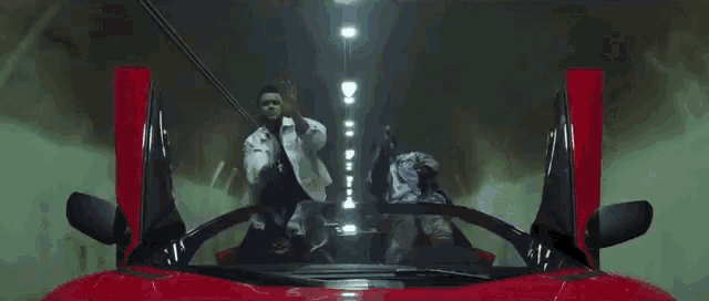 a group of people are riding in a red sports car .