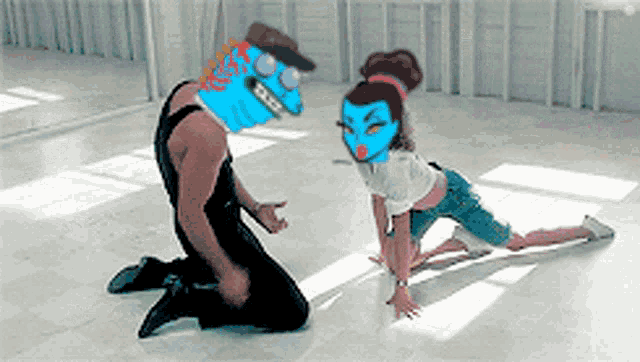 a man with a blue mask on his head kneeling next to a woman with a blue mask on her head