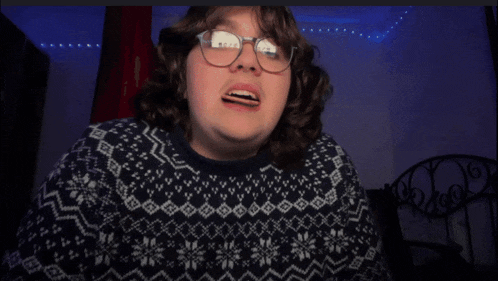 a person wearing glasses and a sweater with snowflakes