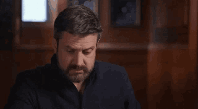 a man with a beard is sitting at a table in a room .
