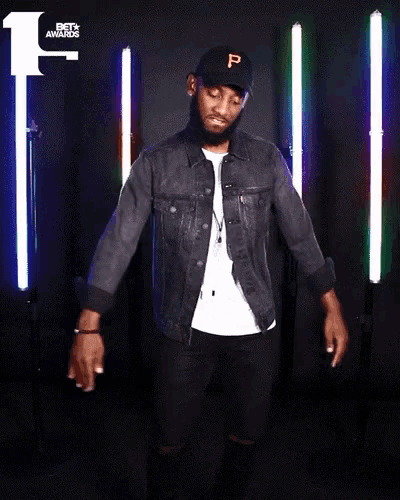 a man wearing a denim jacket and a black hat with the letter p on it