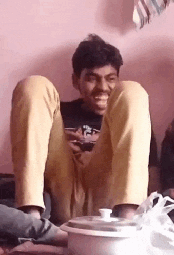 a man is sitting on the floor with his legs crossed and a pot in the background .