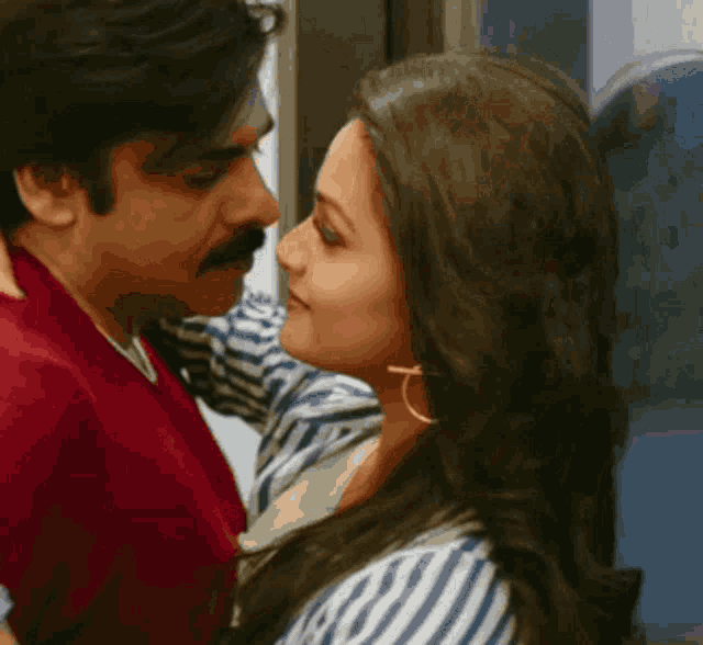 a man and a woman are kissing each other in front of a window .