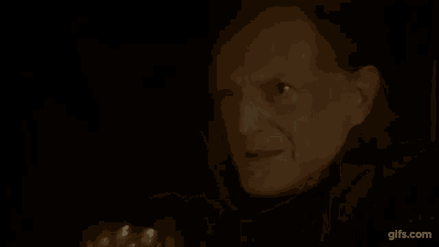 a man is drinking a glass of wine in a dark room .