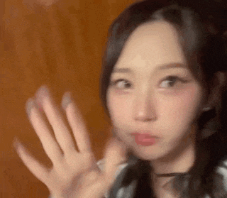 a close up of a woman 's face with her hands up .