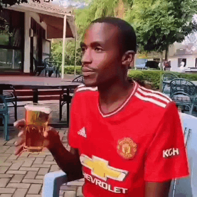a man wearing a red chevrolet jersey is holding a glass of beer
