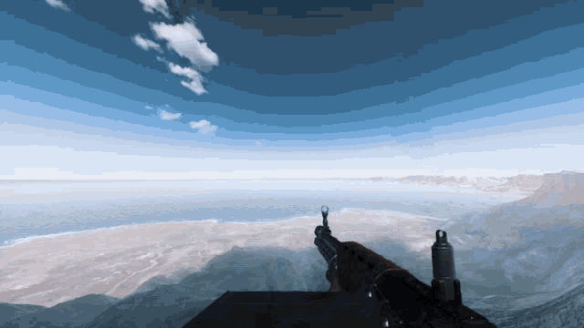 a person holding a gun in front of a body of water and mountains