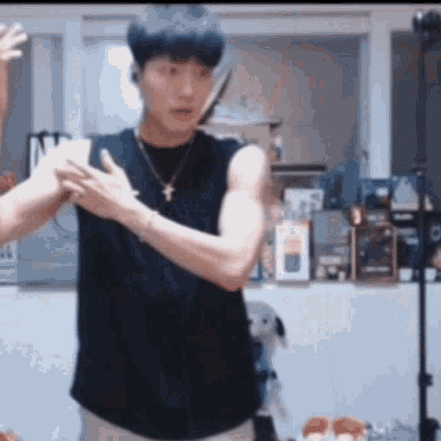 a man in a black tank top is holding a knife in his hand in a room .