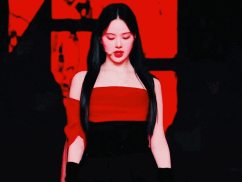 a woman with long black hair is wearing a red top and black skirt
