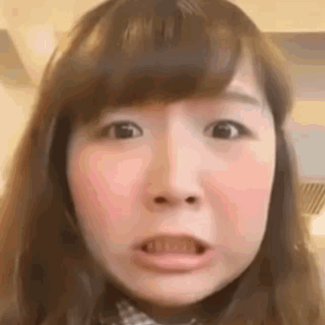 a close up of a woman 's face with her mouth open and a surprised look on her face .