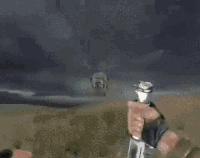a person holding a gun in front of a helicopter with the number 6 on it