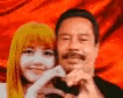 a man and a woman are posing for a picture and making a heart shape with their hands .