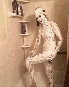 a woman covered in shaving cream standing in a shower