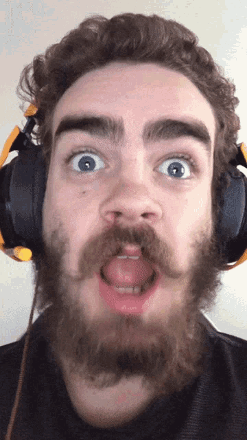 a man with a beard and headphones making a funny face