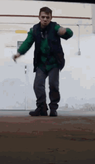 a man in a green vest is dancing in a room