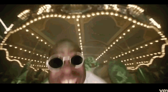 a man wearing sunglasses is riding a merry go round at an amusement park