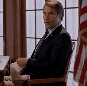 a man in a suit and tie is sitting in a chair .