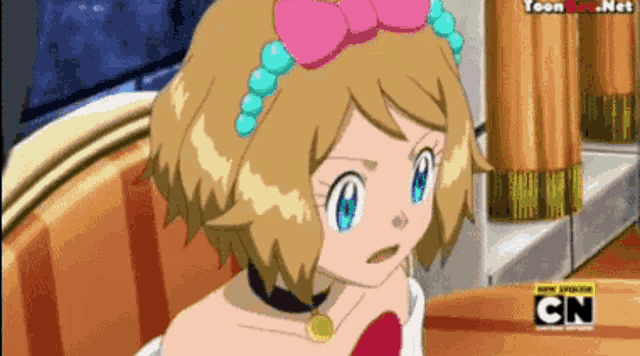 a girl with a pink bow on her head is sitting at a table with cn written on the bottom of the screen