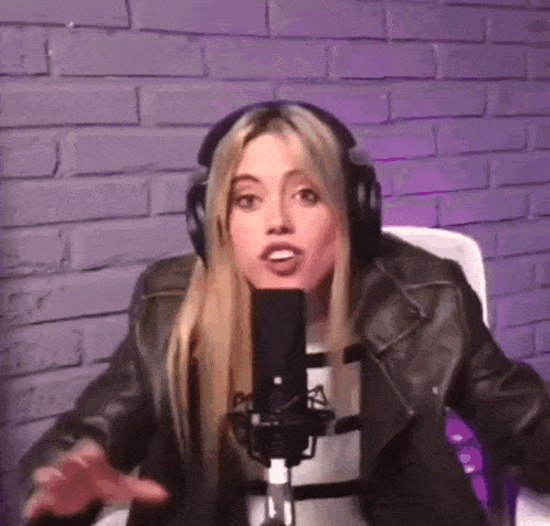 a woman wearing headphones is sitting in front of a microphone and making a funny face .