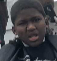 a young boy is getting his hair cut by a barber .