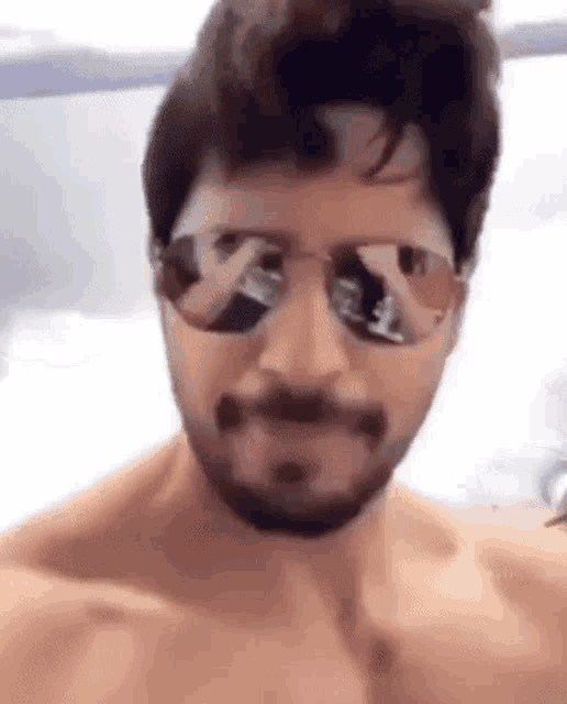 a shirtless man with a beard is wearing sunglasses and a mustache .