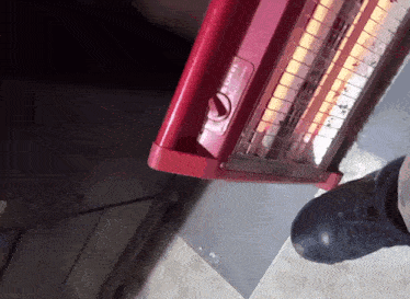 a person standing next to a red heater that says ' heater ' on the side