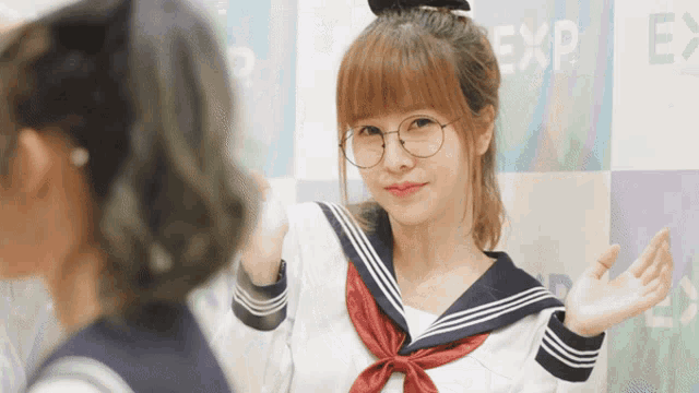 a girl wearing glasses stands in front of a wall with the word exp written on it