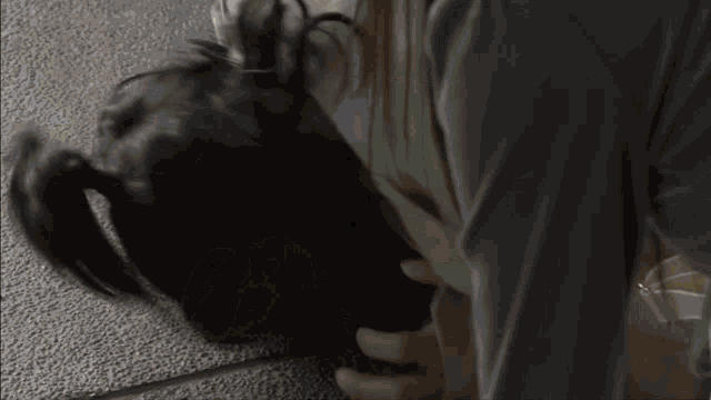a woman in a gray sweater is holding a black bag