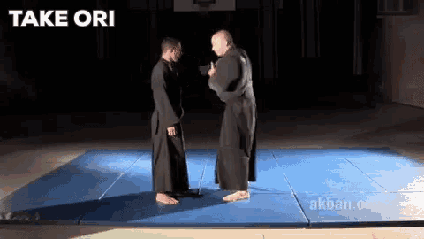 two men are standing on a blue mat with the words take ori written above them