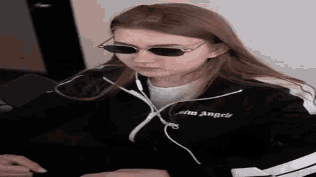 a woman wearing sunglasses and headphones is sitting at a desk .