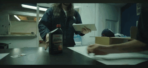 a bottle of gear oil sits on a table next to a man