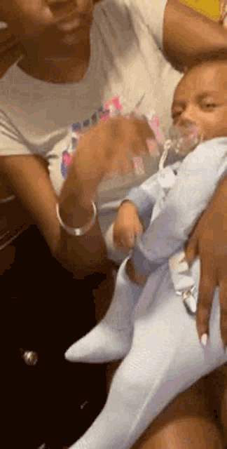 a woman is holding a baby in her arms with a pacifier .