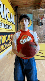 a man wearing a crush shirt is holding a basketball on a basketball court