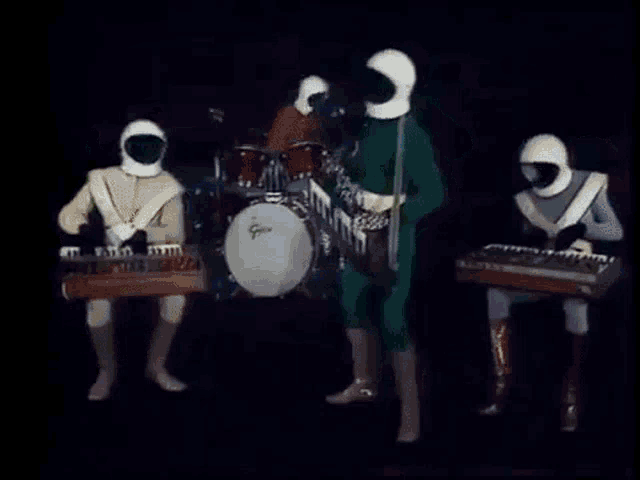 a group of people in space suits are playing keyboards and drums .