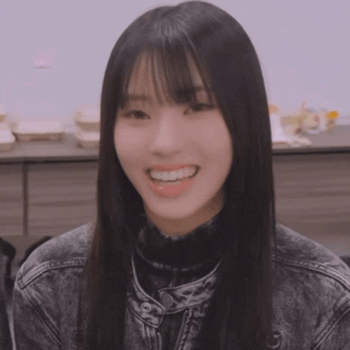 a girl with long black hair and bangs is smiling