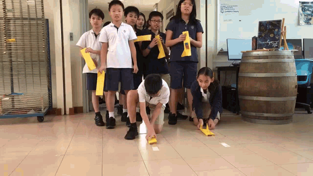 a group of children are playing a game in a hallway with a sign that says ' science agency '