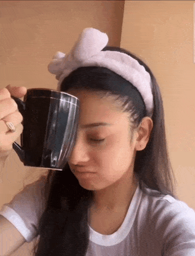 a woman wearing a headband is drinking from a black coffee mug