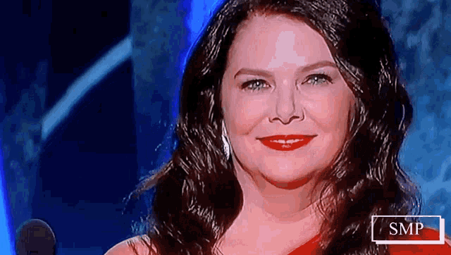 a woman in a red dress is smiling on a television screen
