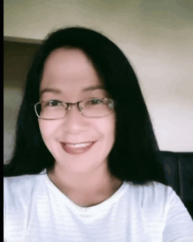 a woman wearing glasses and a white shirt smiles at the camera