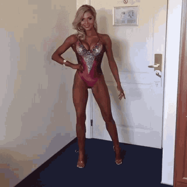 a woman in a pink swimsuit stands in a hallway