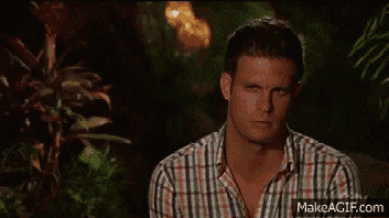 a man in a plaid shirt is making a funny face in front of some plants .