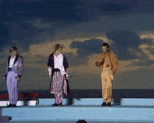 a group of people are standing on a stage in front of the ocean